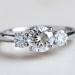 Elegant three stone engagement ring with diamond center and side stones on a white gold band
