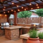 Rustic stone outdoor grill area with built-in grill and wooden pergola