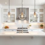 Three glass globe pendant lights hanging over a white marble kitchen island