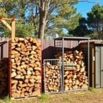 Various outdoor firewood storage solutions including racks, sheds, and covered holders arranged in a backyard setting