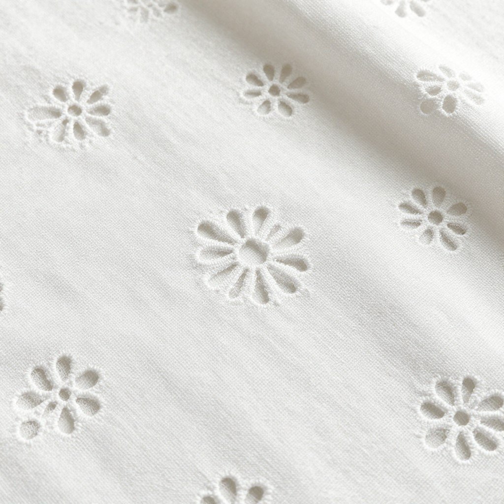 Close-up of cotton eyelet fabric showing its decorative perforated pattern