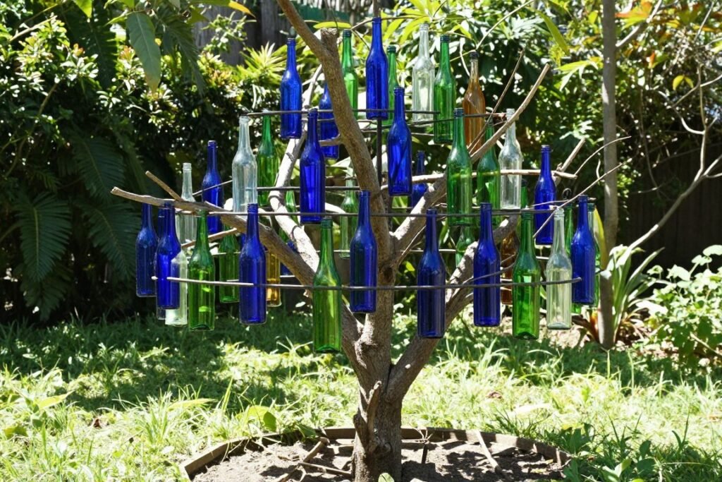 Colorful bottle tree with blue and green glass bottles, easy backyard ideas on a budget