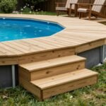 Partial wooden deck attached to one side of an above ground pool with steps and a small seating area