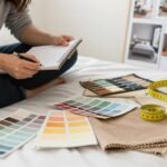 Person planning bedroom makeover with notebook, paint swatches, and measuring tape