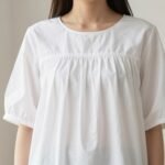 Woman wearing a classic white babydoll top with empire waistline and flowy fabric