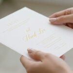 Woman with elegant neutral manicure holding a wedding invitation