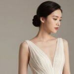 Woman with sleek low bun wedding guest hairstyle wearing formal gown