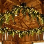 42 Stunning Barn Wedding Decorations for Your Pinterest-Perfect Celebration Barn wedding ceiling decorated with string lights and greenery garlands hanging from wooden beams