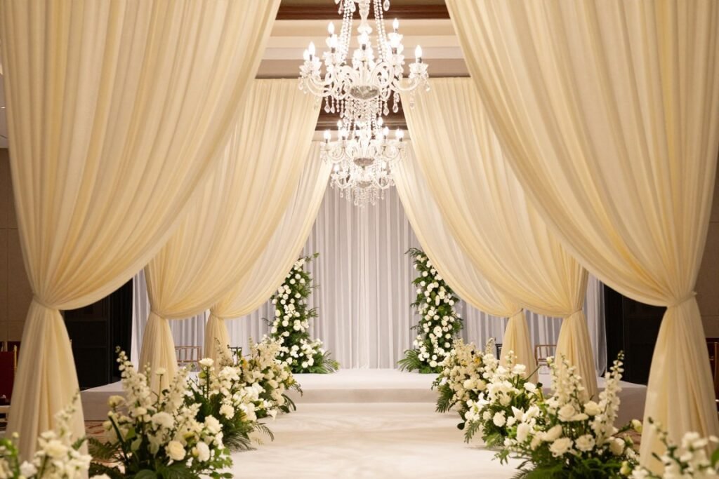 Draped fabric wedding entrance with chandelier and floral accents