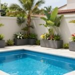 Creating a Resort-Like Oasis with Planters Around Pool Elegant modern pool surrounded by large contemporary planters with tropical plants creating a resort-like atmosphere