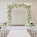 Elegant wedding ceremony setup with floral arch, white chairs, and aisle decorations