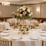 Elegant wedding reception hall with multiple round tables decorated with white linens and floral centerpieces