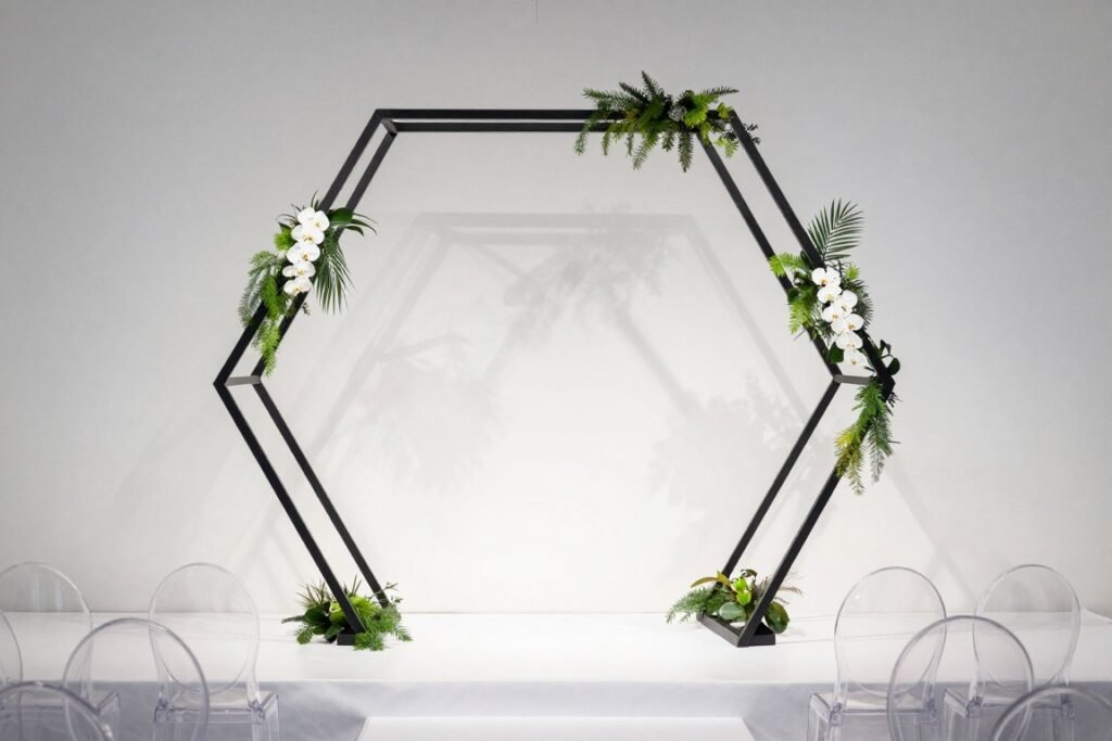 Modern geometric hexagon wedding arch with minimal floral accents