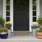 Various front porch planters made of different materials including terra cotta, ceramic, metal, and wood arranged on a stylish front porch