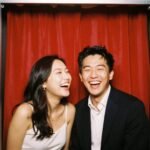 couple laughing together in vintage photobooth with curtain background