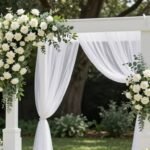 elegant wedding arch decorated with white flowers and greenery at outdoor ceremony