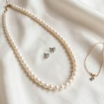 elegant wedding jewelry ideas for bride featuring pearl necklace and diamond earrings on silk fabric