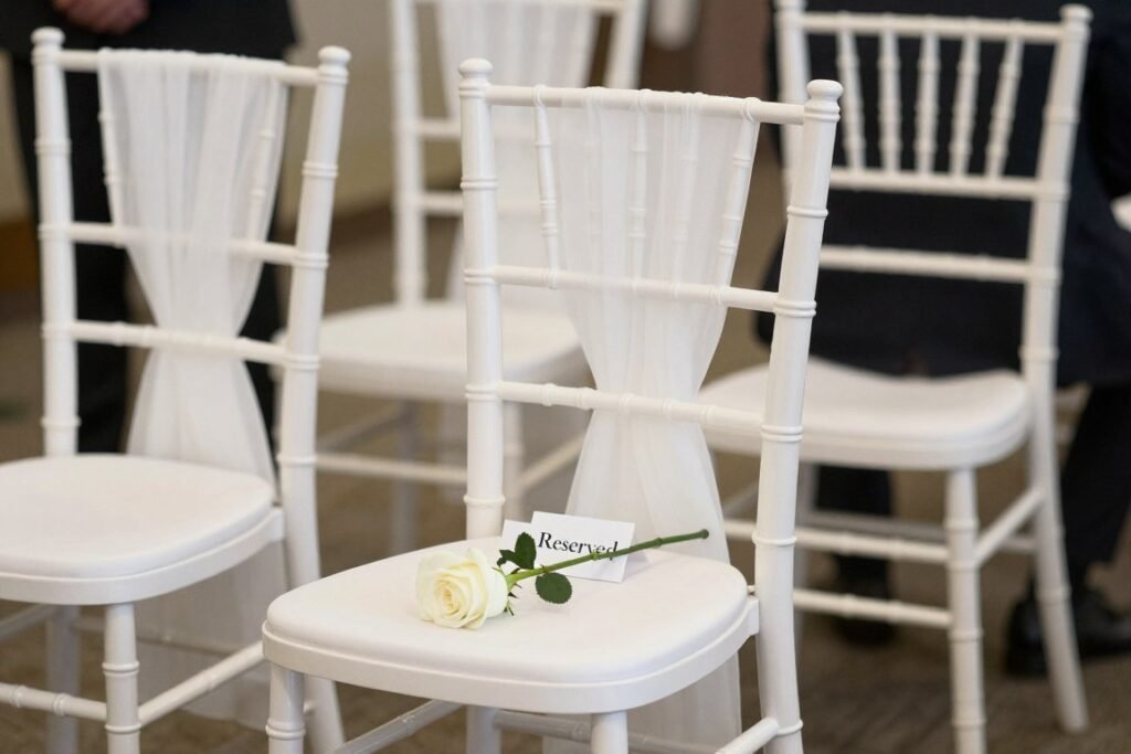 empty ceremony chair with single white rose and in memory sign