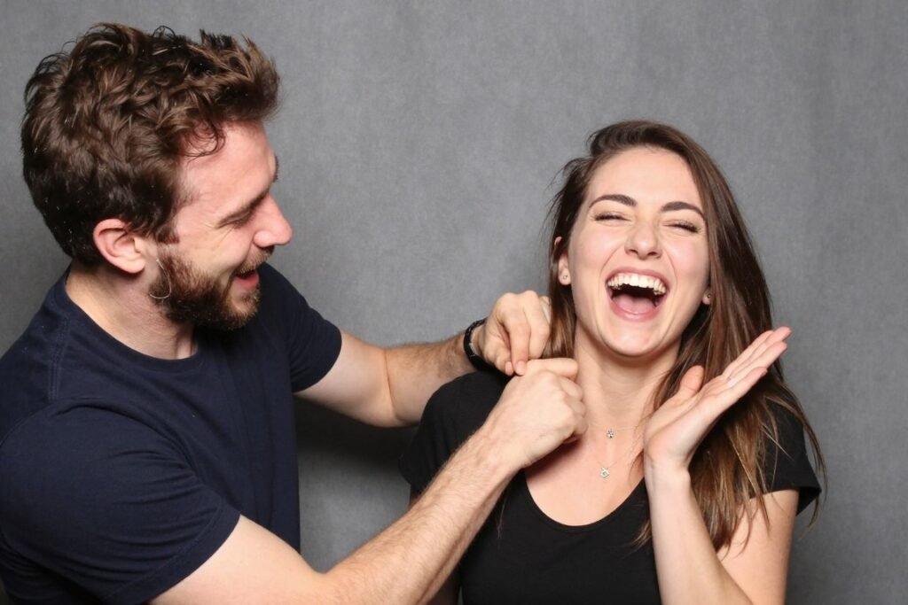 man tickling woman while she laughs uncontrollably in photobooth