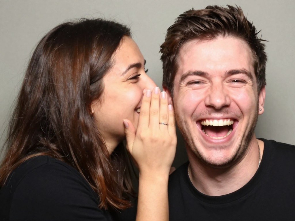 woman whispering in man's ear while he laughs in photobooth